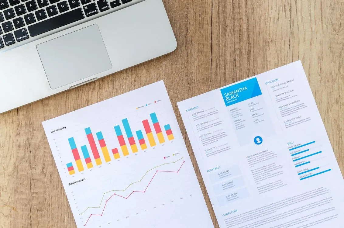 Laptop mit Marketing-Auswertungen und Diagrammen auf einem Holztisch